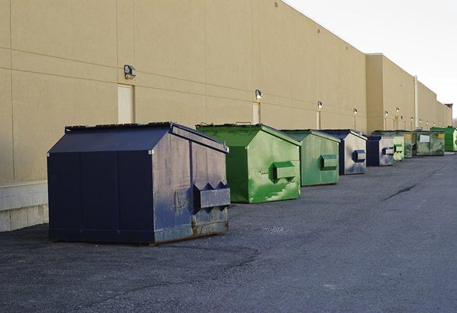 a series of colorful, utilitarian dumpsters deployed in a construction site in Blooming Grove